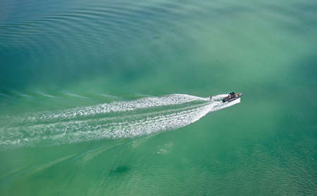 Aerial view wakeboarding on the green lake behind a motorboat.