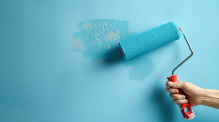 Paint roller in hand on blue background with copy space for textの素材