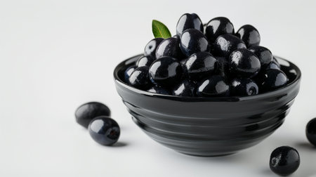 Black olives in a bowl on white background, close-upの素材