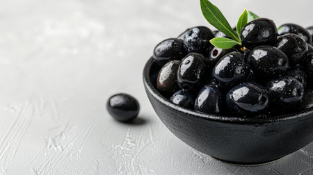 Black olives in a bowl on a white textured background.の素材