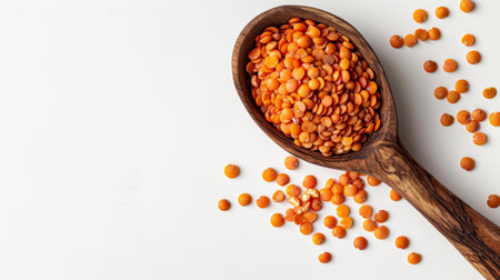 Red lentils in a wooden spoon on a white background, top viewの素材