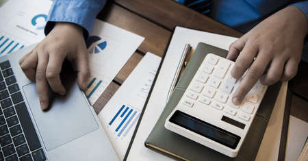 Financial businessmen use laptop to analyze marketing strategies and real estate data to reduce...