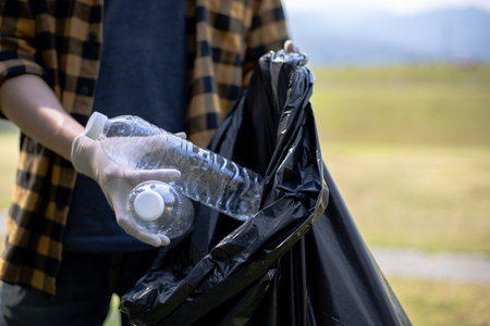 Male volunteers carry water bottles or plastic bags that have fallen in the park put them in trash cans, Environmental protection or volunteering for charity, Waste disposal through recycling.の写真素材
