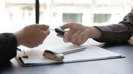 Car salesman gave the keys to the customers who signed the purchase contract legally, Successful completion of car sales, Purchase contract and key delivery.の写真素材