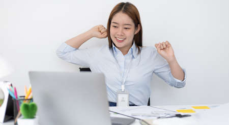 Young Asian female employee is doing a relaxing posture after a hard morning's work, Happy women resting at work after work is finished, Fatigue is eased, Women working in the office.の写真素材