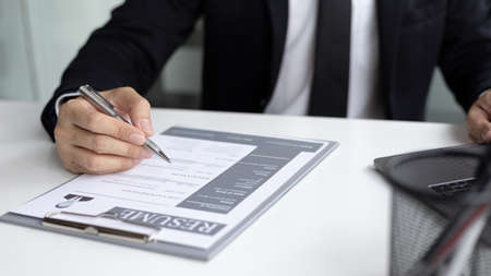Man in a black suit is sitting in the office reading the history of the staff, officer or supervisor...