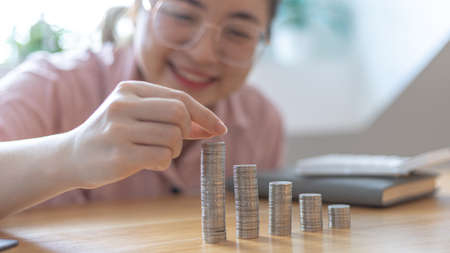 Woman's hands put the coins arranged in steps, Managing your finances or saving money for future use, Saving for investment, Saving money for business growth or long-term profitability.の写真素材