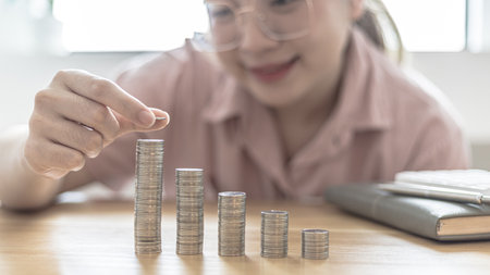 Woman's hands put the coins arranged in steps, Managing your finances or saving money for future use, Saving for investment, Saving money for business growth or long-term profitability.の写真素材