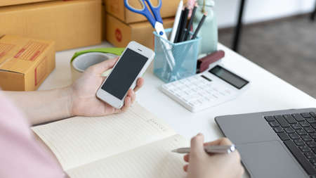 Young woman selling products online was talking on the phone to receive an order from a customer who...
