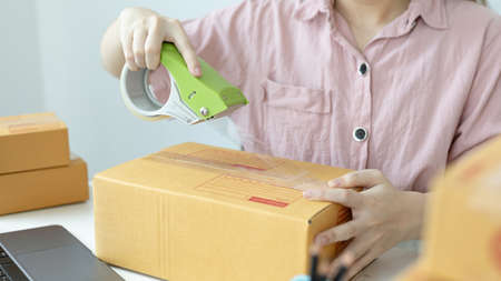 Woman in a pink shirt is packing in the mailbox to prepare to deliver it to the customer, New...