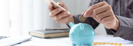 Businessmen put coins in a piggy bank and record income - income tax expenses in the office, Financial accounting and save money concept.の写真素材