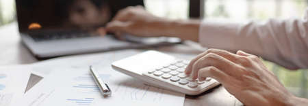 Business men analyze financial graphs and find break-even points for investments in order to reduce...