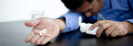 Asian man is seriously ill, In his hand had a medicine and sat sick in his office.の写真素材