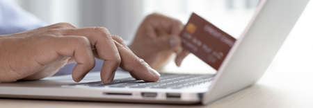Young Asian businessman uses a credit card to shop online via laptop in his office, Buy online,...