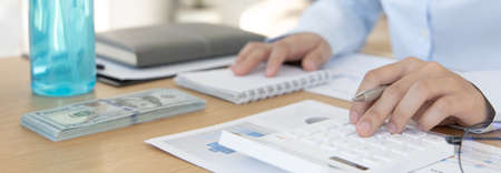 Accounting businessmen are calculating income-expenditure and analyzing real estate investment data, Detention periods or social distances, Alcohol bottle, Financial and tax systems concept.の写真素材