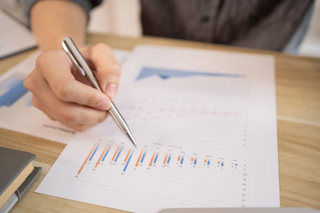 Close-up of a pen pointing at a graph, Financial statistics and calculating corporate returns in private offices, Market research reports and income statistics, Financial and Accounting concept.の写真素材