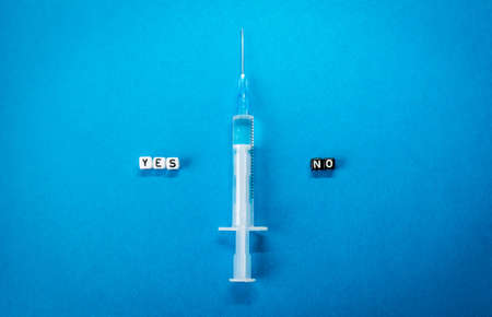 Yes No words made of square letters and a syringe on blue background. Pros and cons of  vaccine, concerns and doubts about   vaccination conceptの写真素材