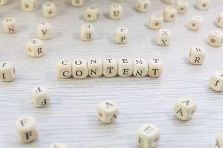 Word Content made with block wooden letters cubes in centre surrounded by pile of other letters on...