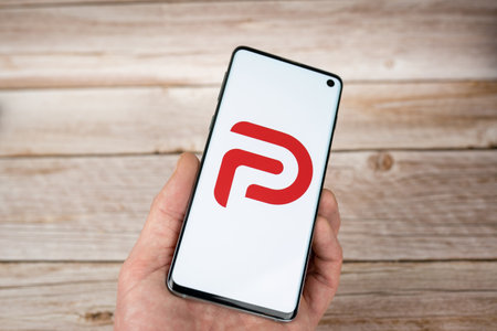 Man holding a smarphone with Parler logo, a free speech social network app. Red logo on white backgroundのeditorial素材