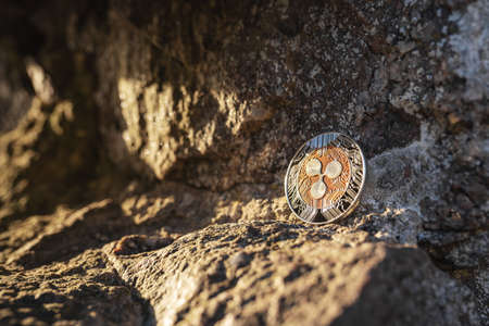 Close-up of XRP Ripple on a stone outdoor with soft sunset light on rocks background with copy...