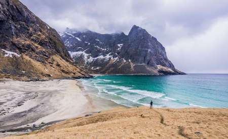 View of Kvalvika Beach, Hike to Ryten viewpoint, Lofoten Islands, Norway. White-sand Arctic Beach, top view. Single tourist taking selfie overlookingの写真素材
