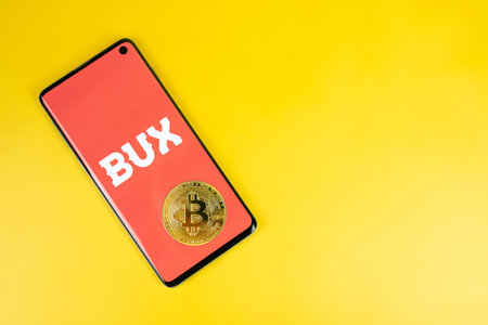Bux icon on phone with Bitcoin on yellow backgroundのeditorial素材