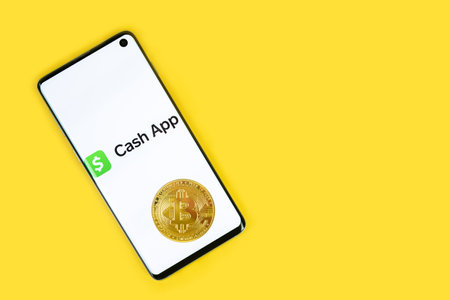 Cash app icon on phone with Bitcoin on yellow backgroundのeditorial素材