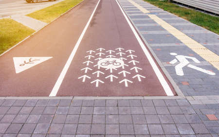Cycle lane, running track and a pavement. Cycle path marked with signs and arrows painted on red...