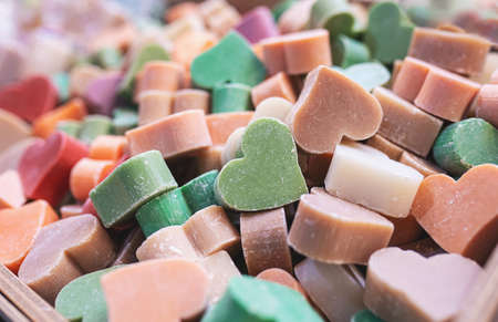 Multicolored handmade soaps in the shape of heart close-up. Bunch of small organic soap bars, beautiful background with selective soft focus.の写真素材