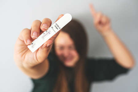 Negative rapid antigen COVID-19 test in hand of unrecognizable blurred person. Happy woman shows her test result. Travel during the coronavirus pandemic, avoid quarantine, new normal concept.の写真素材