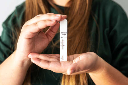 Positive rapid antigen COVID-19 test result in hands f unrecognizable person. Woman holds a quick...
