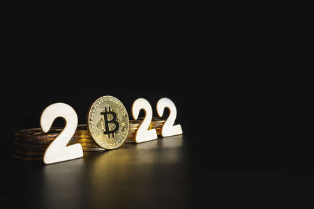 Bitcoin 2022. Single Bitcoin gold coin next to 2 numbers on black background with copy space. Price, future value of BTC crypto prediction concept.の写真素材