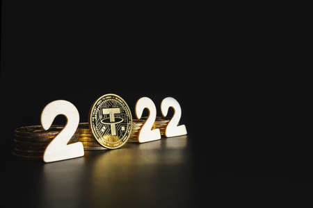 Tether in 2022. Single Tether gold coin next to the year numbers on black background with copy space for text. Value, market cap prediction concept.の写真素材