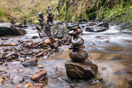 Stone stacking or rock balancing at river. Zen balanced pebbles stack art. Beautiful peaceful calm idyllic landscape background with long exposure. Relaxation, environment and ecosystem concept.の写真素材