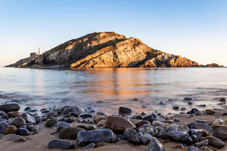 Small island near Mumbles Head and Lighthouse at sunset, Gower Peninsula, South Wales, The United Kingdomの写真素材
