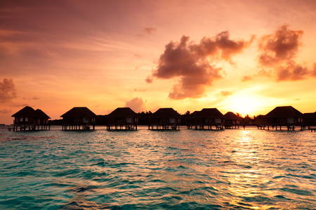 Sunrise over water bungalows on a cloudy day at the end of rainy season in Maldives.のeditorial素材