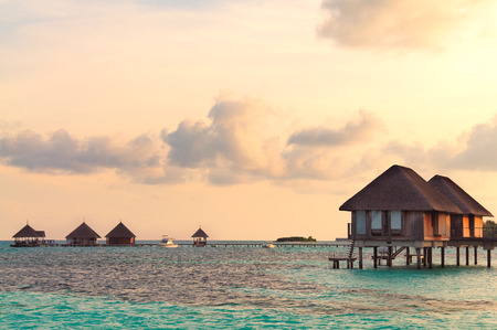 Sunrise over water bungalows on a cloudy day at the end of rainy season in Maldives.のeditorial素材