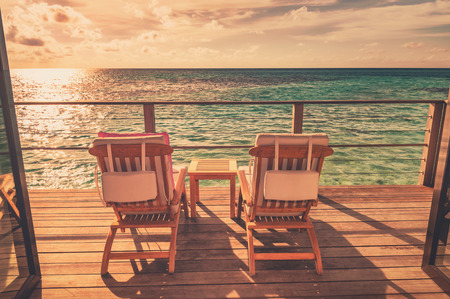 Two deck chairs on a sea view balcony at a tropical resort during sunset in Maldives.の写真素材