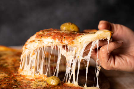 slice of mozarella pizza with tomato sauce, oregano, green olives, lots of cheese