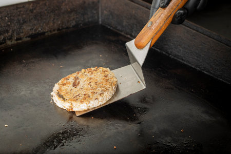 cooking hamburger patty on a frying pan with a knife