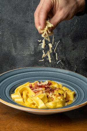 Tasty appetizing classic Italian pasta carbonara with bacon and cheese on a dark backgroundの写真素材