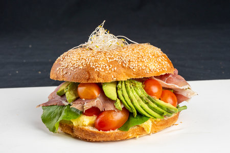 sandwich with ham, avocado, tomato and lettuce on a black backgroundの写真素材