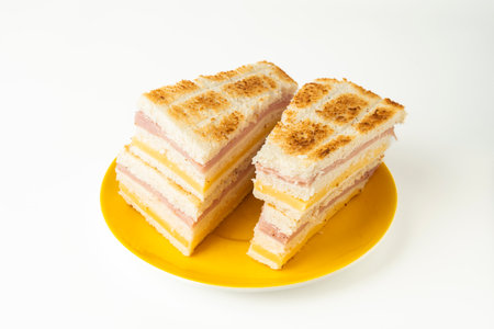 Sandwich with ham and cheese on yellow plate isolated on white backgroundの写真素材
