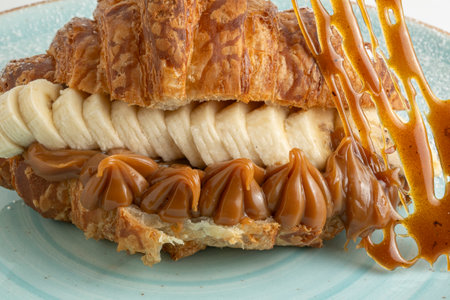 Croissant with caramel and bananas on a plate, close upの写真素材