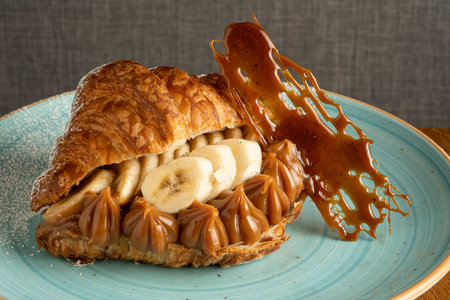 Coffee croissant with banana and caramel on a plateの写真素材