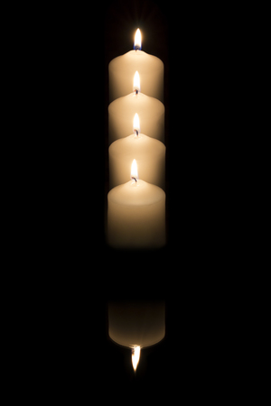 Four candles reflected on dark backgroundの写真素材