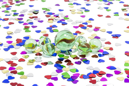 Toy marbles on white background, surrounded by so many multicolor hearts の写真素材