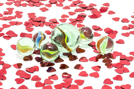 Toy marbles on white background, surrounded by so many red hearts の写真素材