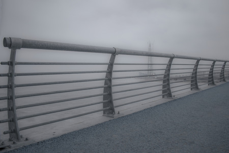 Old rusty metal railings on the bridge. Road with cracked asphalの写真素材