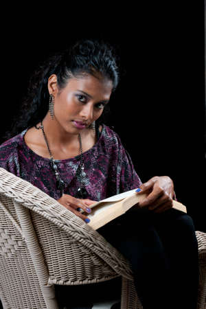 beautiful woman of east indian ancestry sitting in a chair reading a book の写真素材